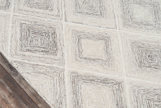 Light gray cement tile with concentric square geometric pattern; wood plank corner visible.