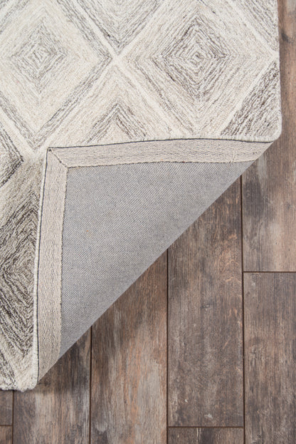 Light gray and white geometric diamond rug with textured pattern, folded corner shows underside on dark wood floor.
