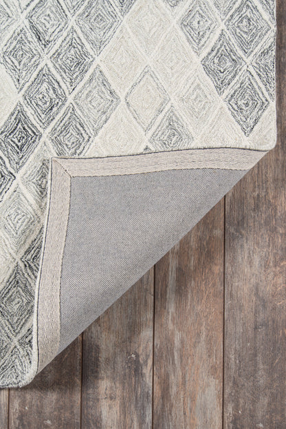 Grey geometric diamond rug with light and dark tones, folded corner reveals backing on wooden floor.