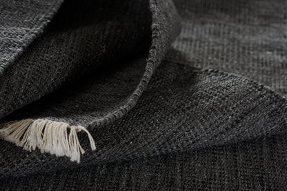 Charcoal grey knitted scarf with white fringe edge, soft wool blend, cozy winter accessory.