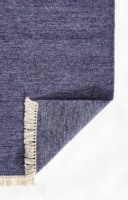 Navy blue woven rug with cream fringe along one edge, folded corner showing texture.
