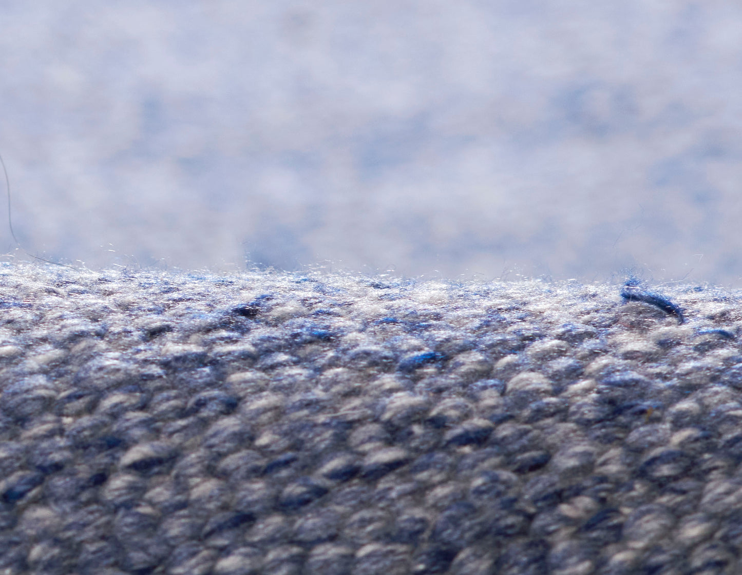 Blue-gray loop-pile rug close-up showing dense, speckled fibers.