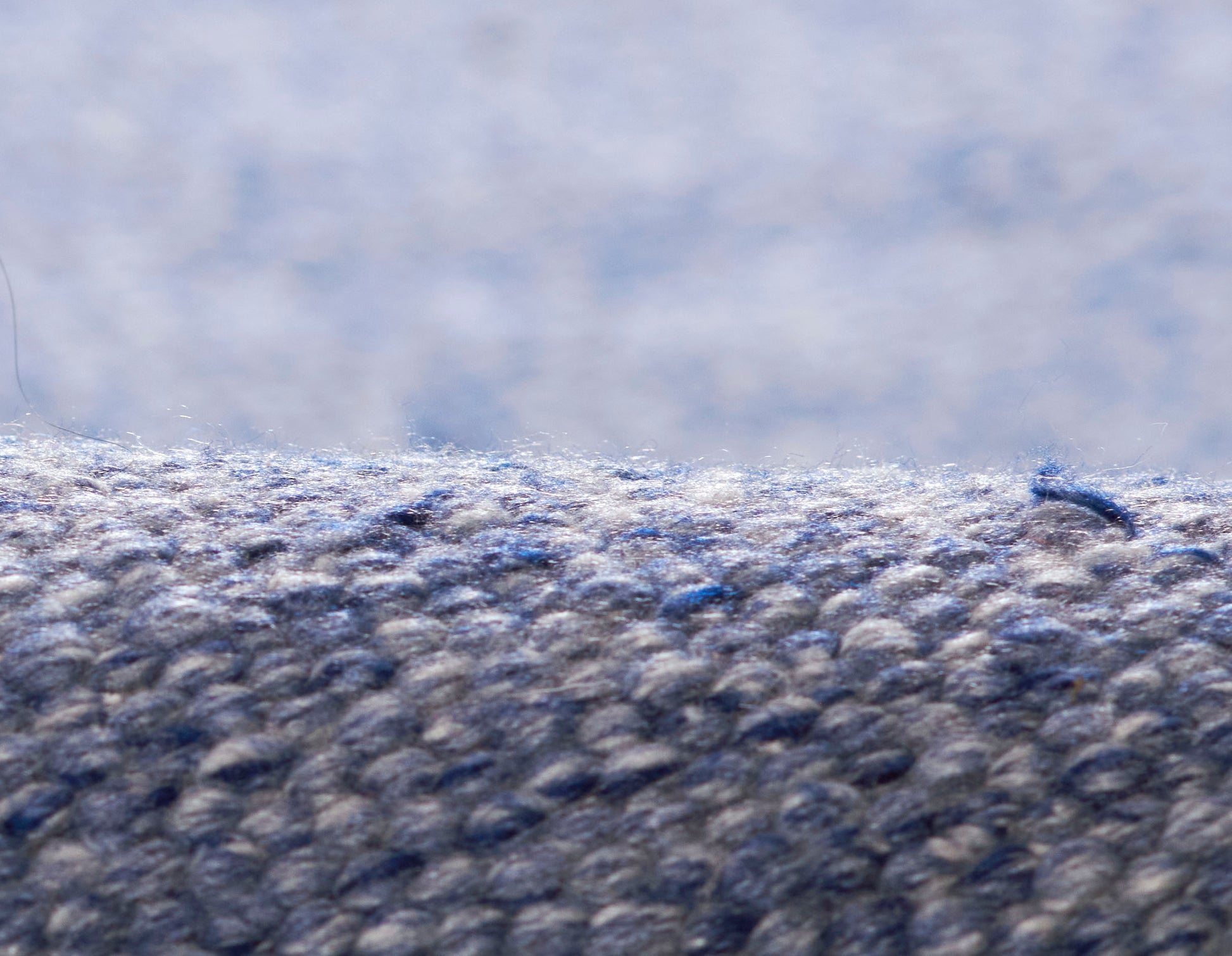 Close-up of blue-gray loop-pile carpet fibers with dense, textured weave.