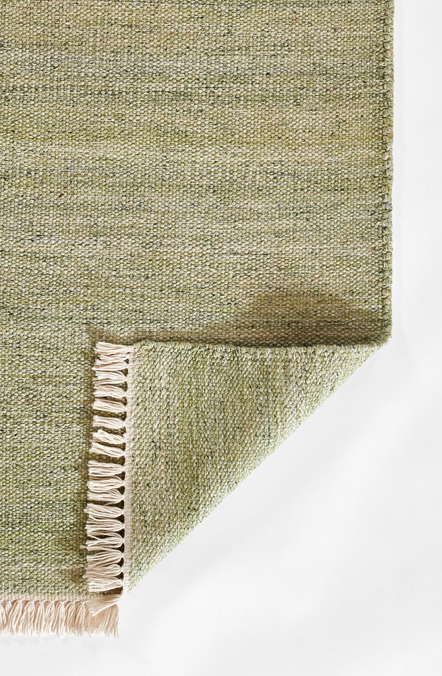 Olive-green textured woven rug with cream fringe, folded at the corner.