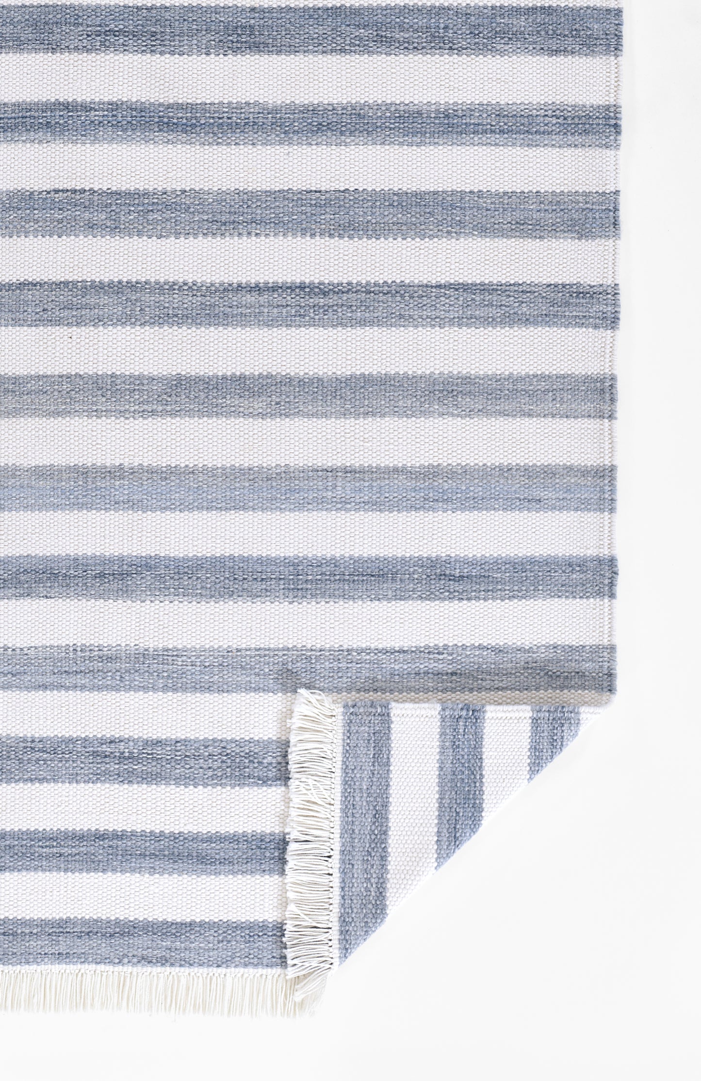 Blue & white striped rug with fringe edges, folded corner.