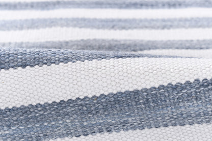 Close-up of blue and white striped woven rug with a textured surface, casual coastal-style.