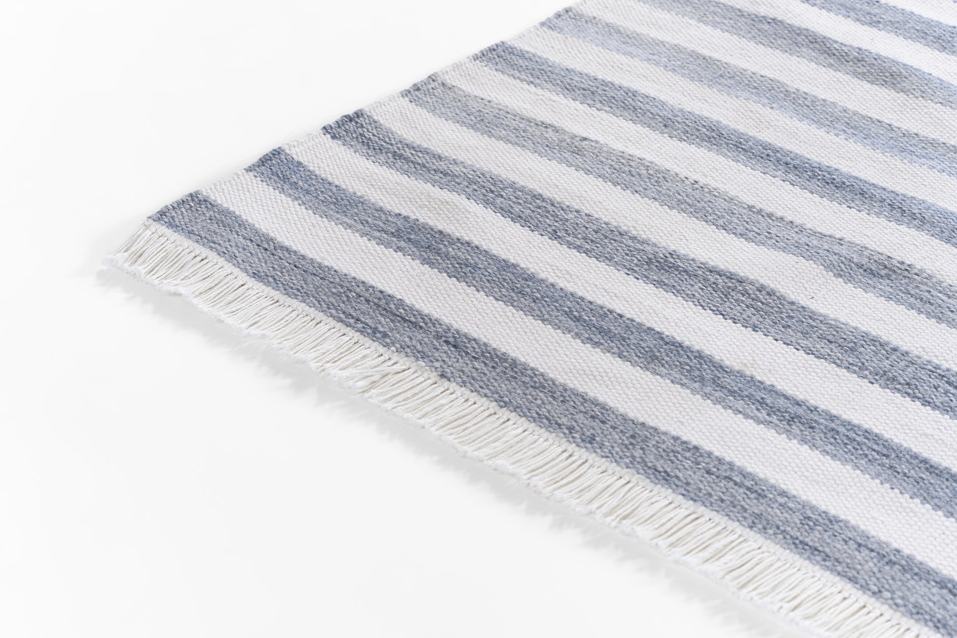 Blue and white striped rug with fringe edging, laid flat.