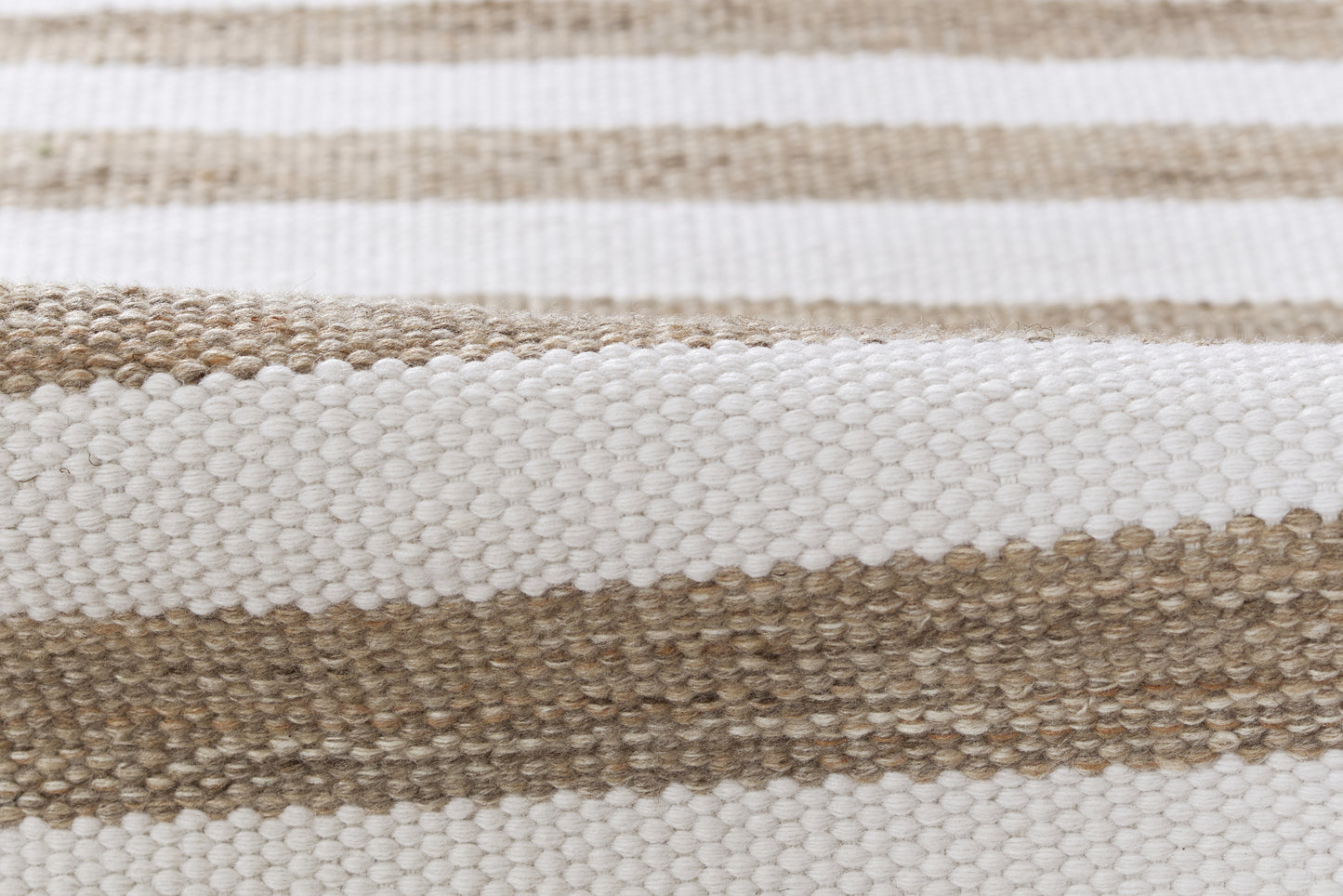 Woven striped rug in ivory white and natural beige; flat-weave texture for casual coastal decor.