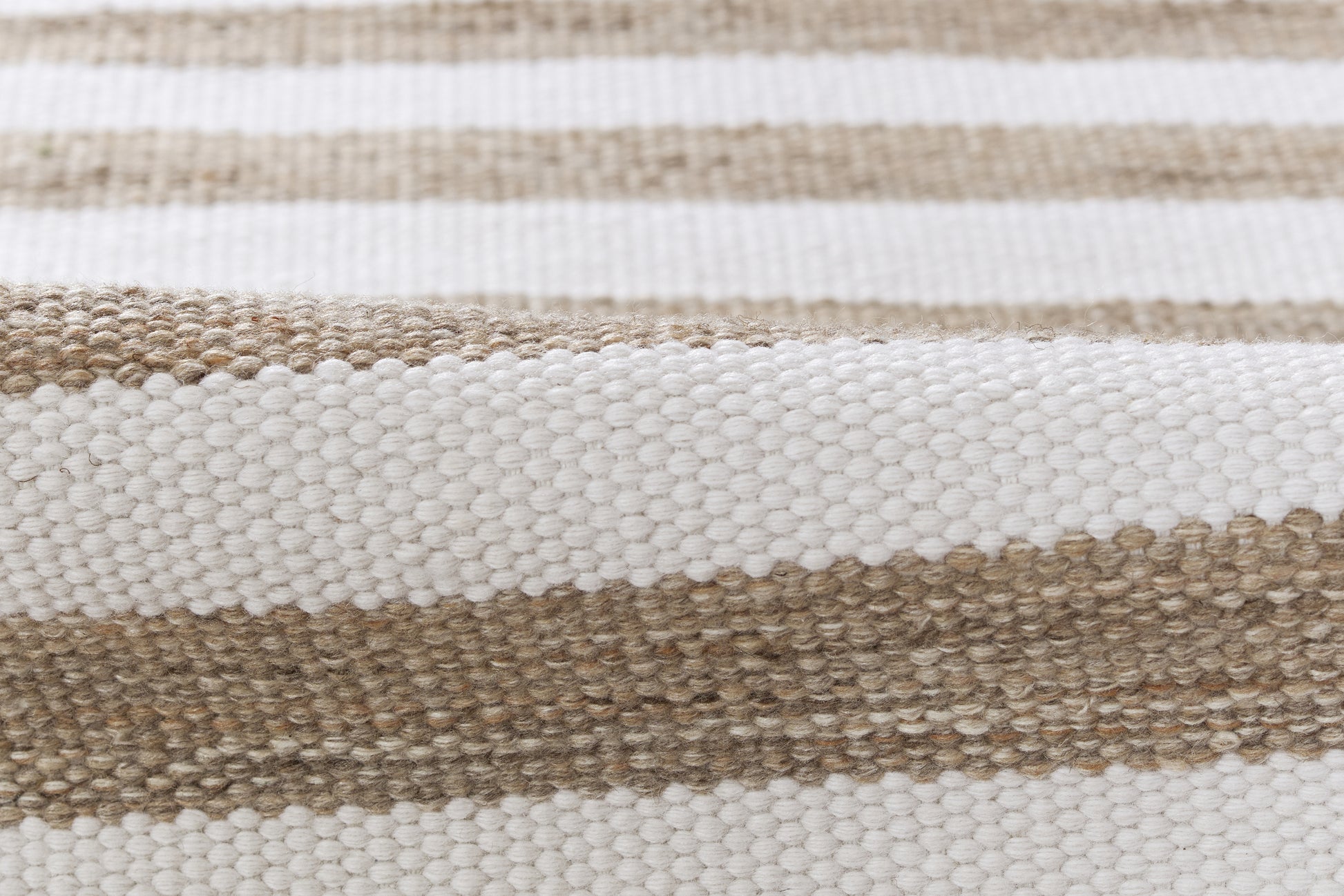 Close-up of a striped woven rug in natural beige and white with a chunky textured weave.