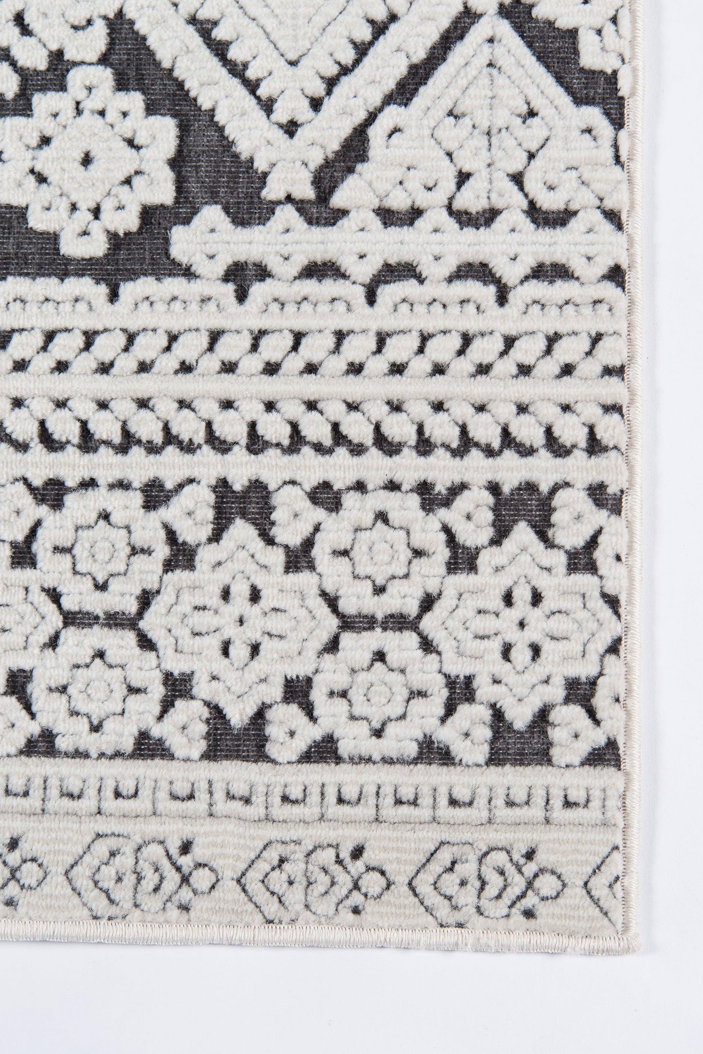 Rectangular runner rug with black base and cream embroidery of geometric floral rosettes and bordered bands, boho Moroccan style.