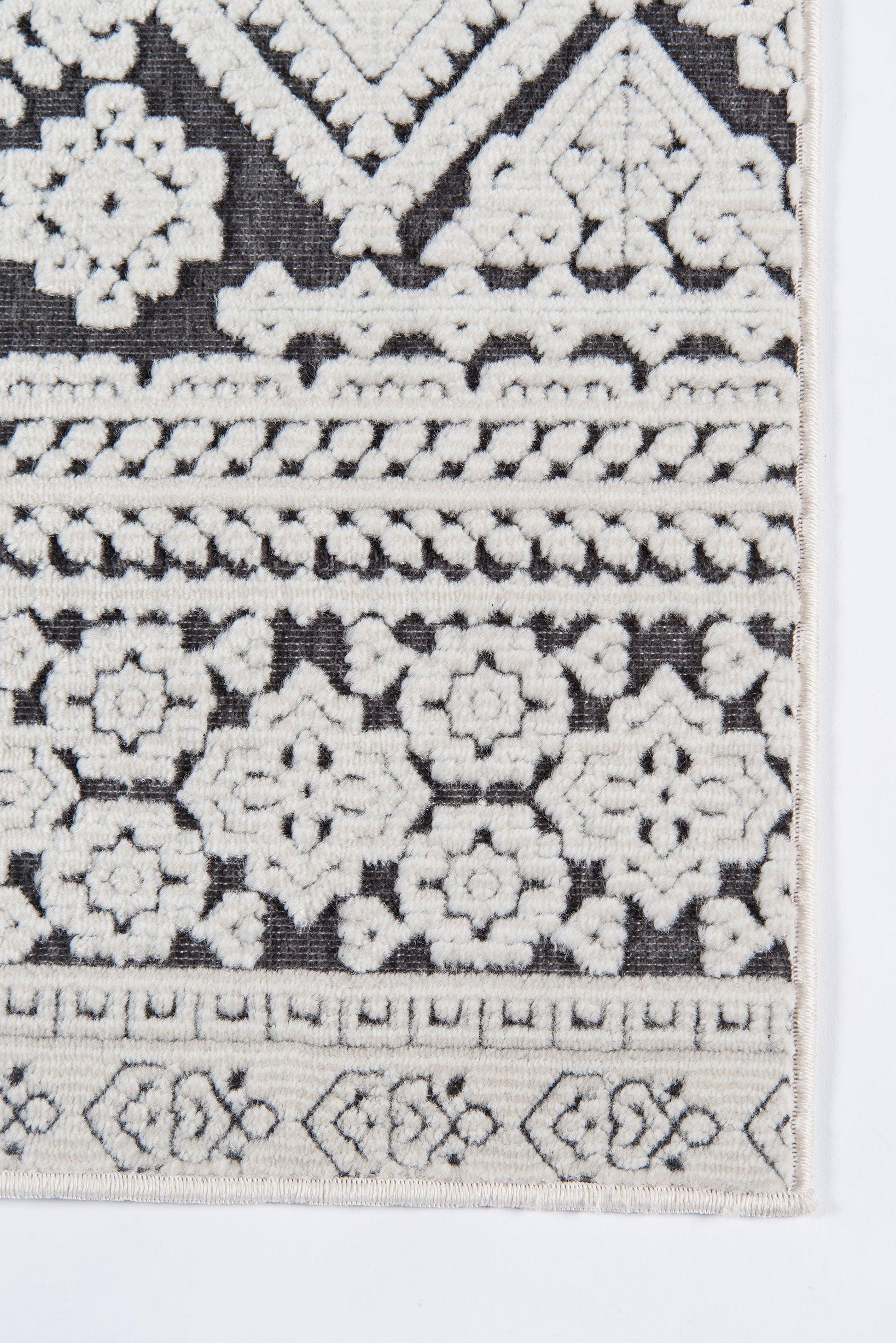 Rectangular runner rug with black base and cream embroidery of geometric floral rosettes and bordered bands, boho Moroccan style.