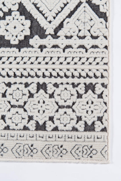 Rectangular runner rug with black base and cream embroidery of geometric floral rosettes and bordered bands, boho Moroccan style.