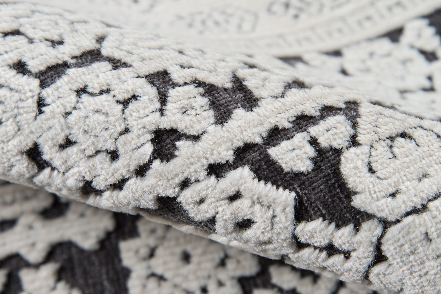 Close-up of cream and charcoal damask floral rug with a textured woven pile.