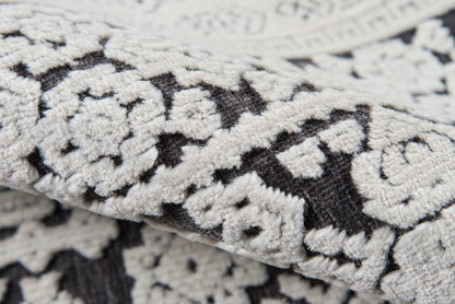Close-up of cream and charcoal damask floral rug with a textured woven pile.
