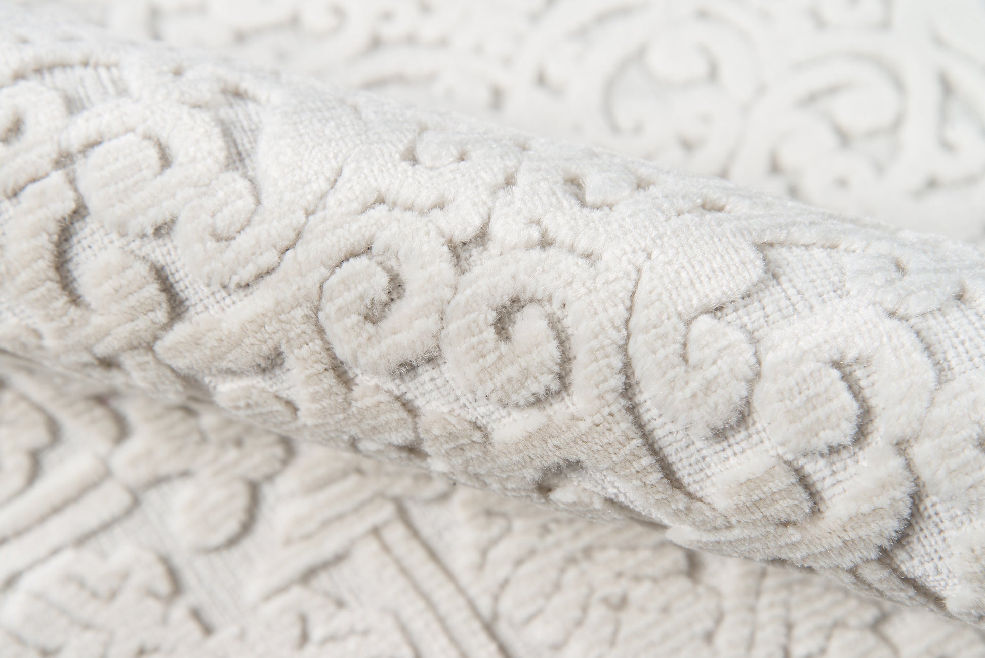Ivory damask jacquard fabric with raised scrolling floral pattern, soft textured upholstery textile.