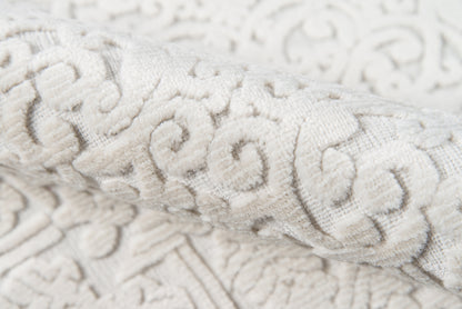 Ivory damask jacquard fabric with raised scrolling floral pattern, soft textured upholstery textile.