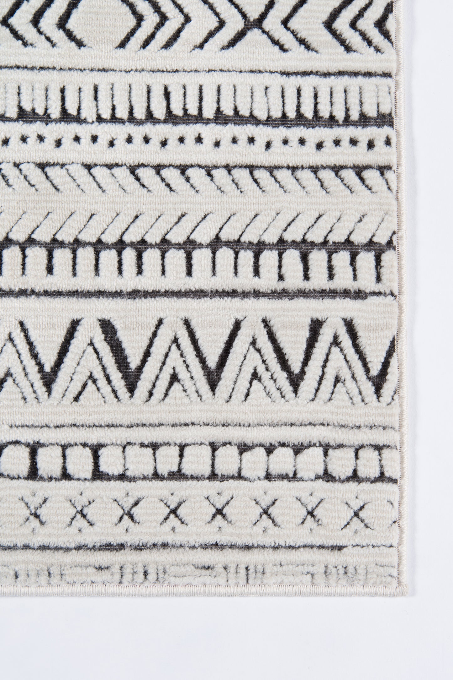 Close-up of a black and ivory geometric woven rug with chevrons, stripes, and fringe along the edge.