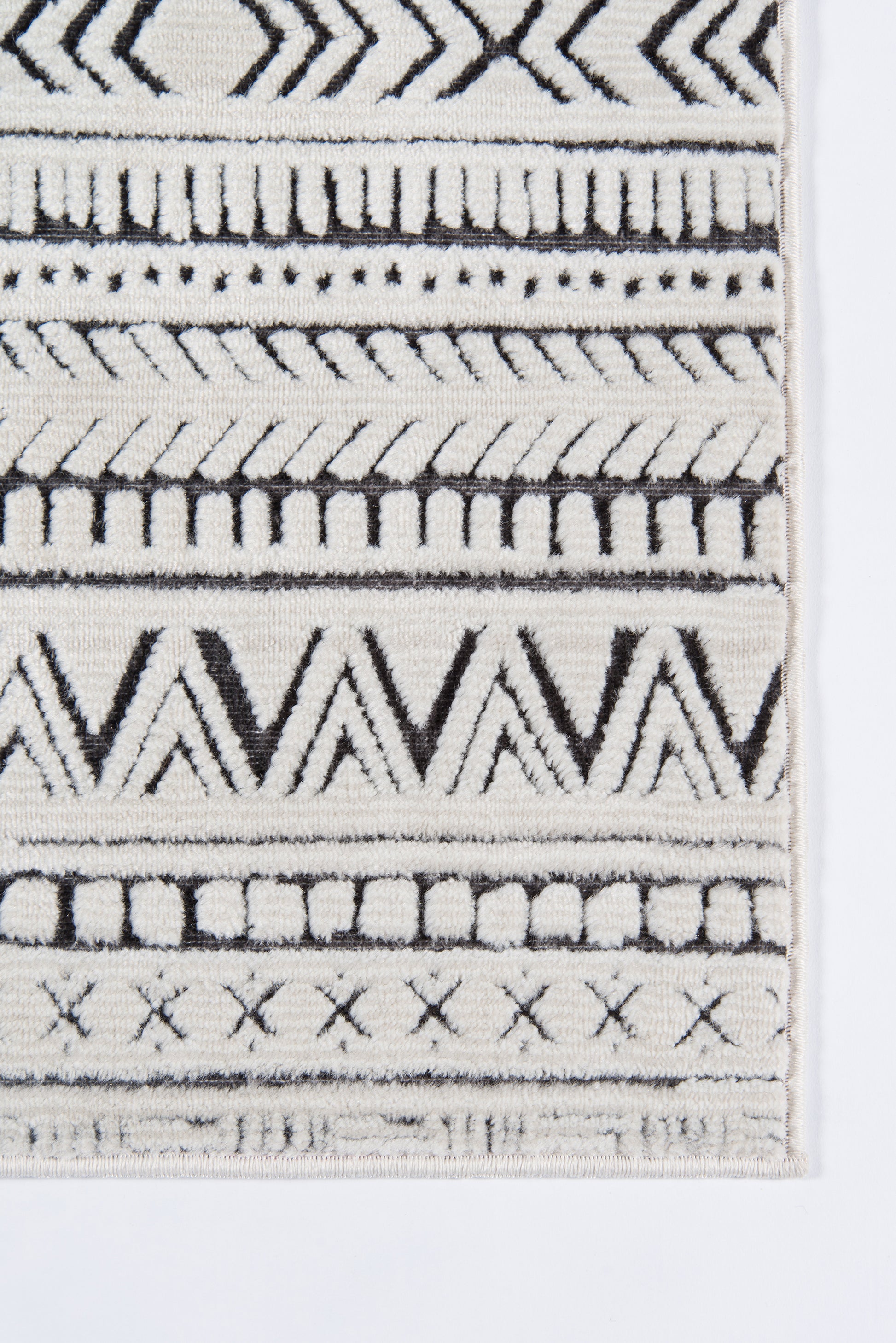Close-up of a black and ivory geometric woven rug with chevrons, stripes, and fringe along the edge.