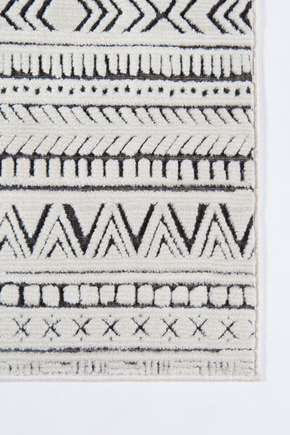 Close-up of a black and ivory geometric woven rug with chevrons, stripes, and fringe along the edge.