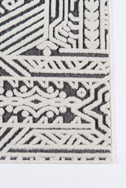 Corner view of a white-on-black geometric woven runner rug with intricate patterns.