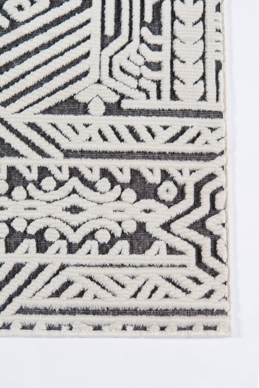 Corner view of a white-on-black geometric woven runner rug with intricate patterns.
