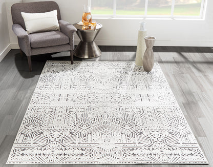 Geometric gray-and-white rug as the main focus, with a gray upholstered armchair beside a metal side table.