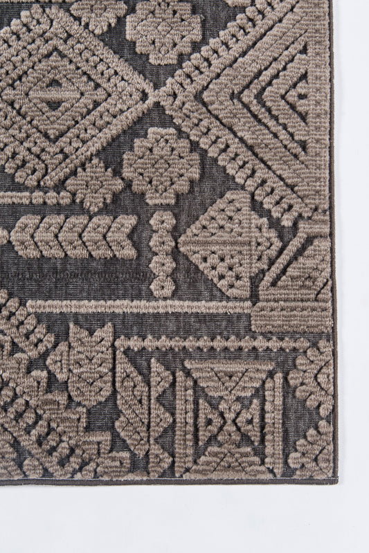 Geometric tribal rug corner in taupe and brown, woven with diamond and floral motifs.
