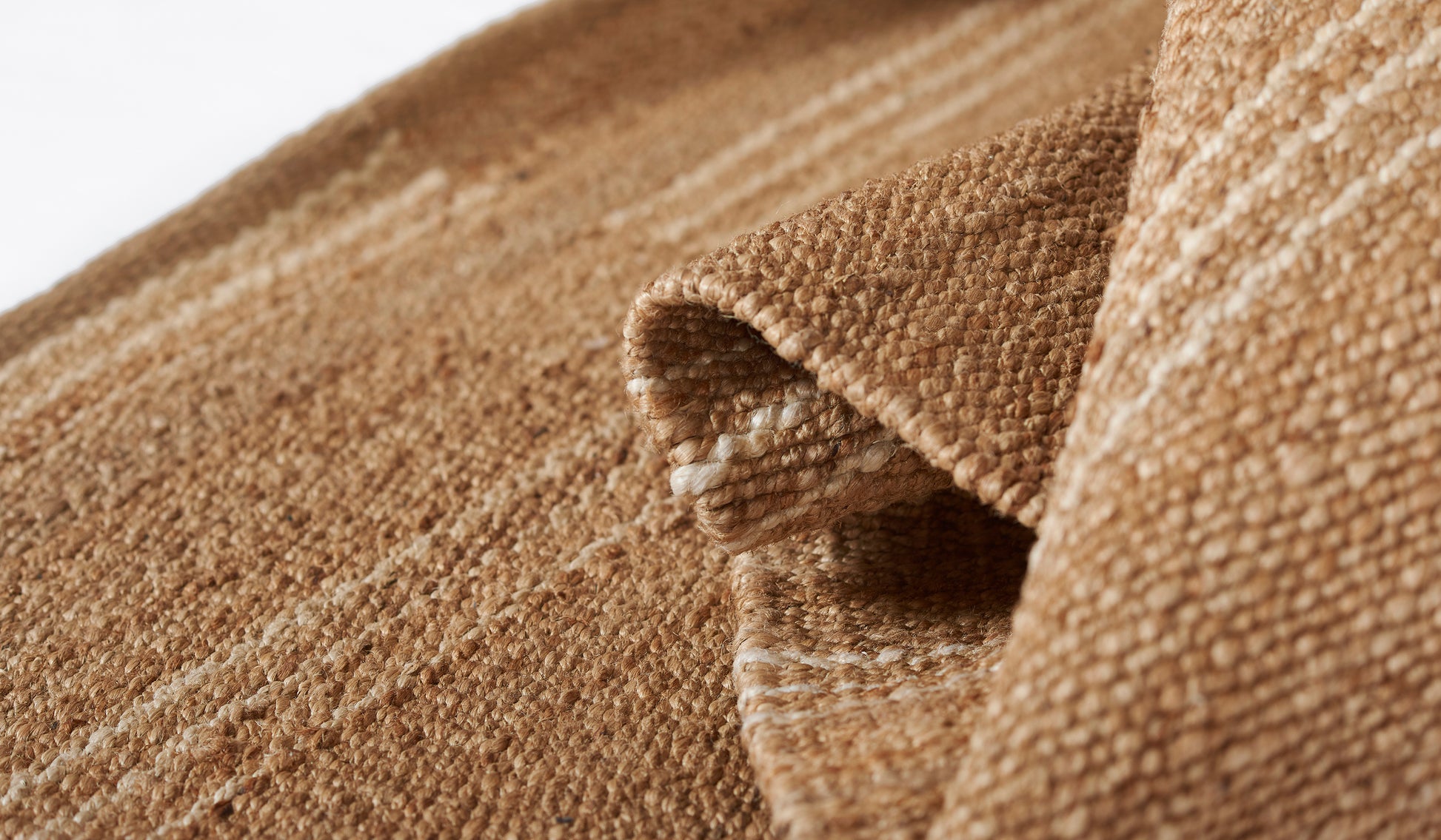Natural beige woven rug with coarse texture and folded edge.