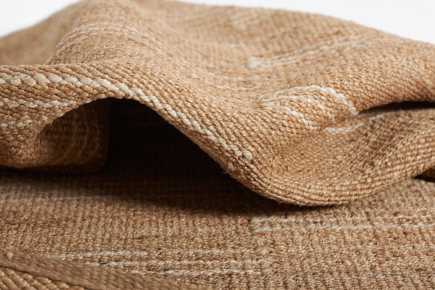 Beige burlap rug, folded, with coarse woven jute texture and natural rustic look.