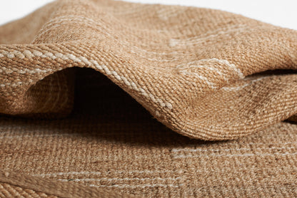 Beige burlap rug, folded, with coarse woven jute texture and natural rustic look.