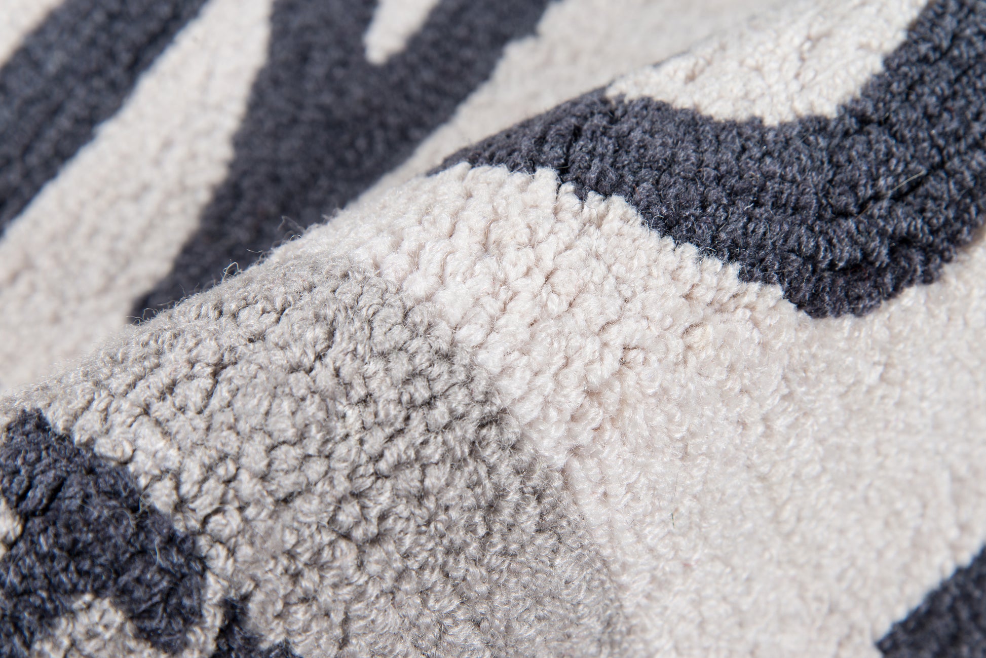 Close-up of a plush boucle rug with an abstract navy, gray, and ivory pattern in thick loop pile.