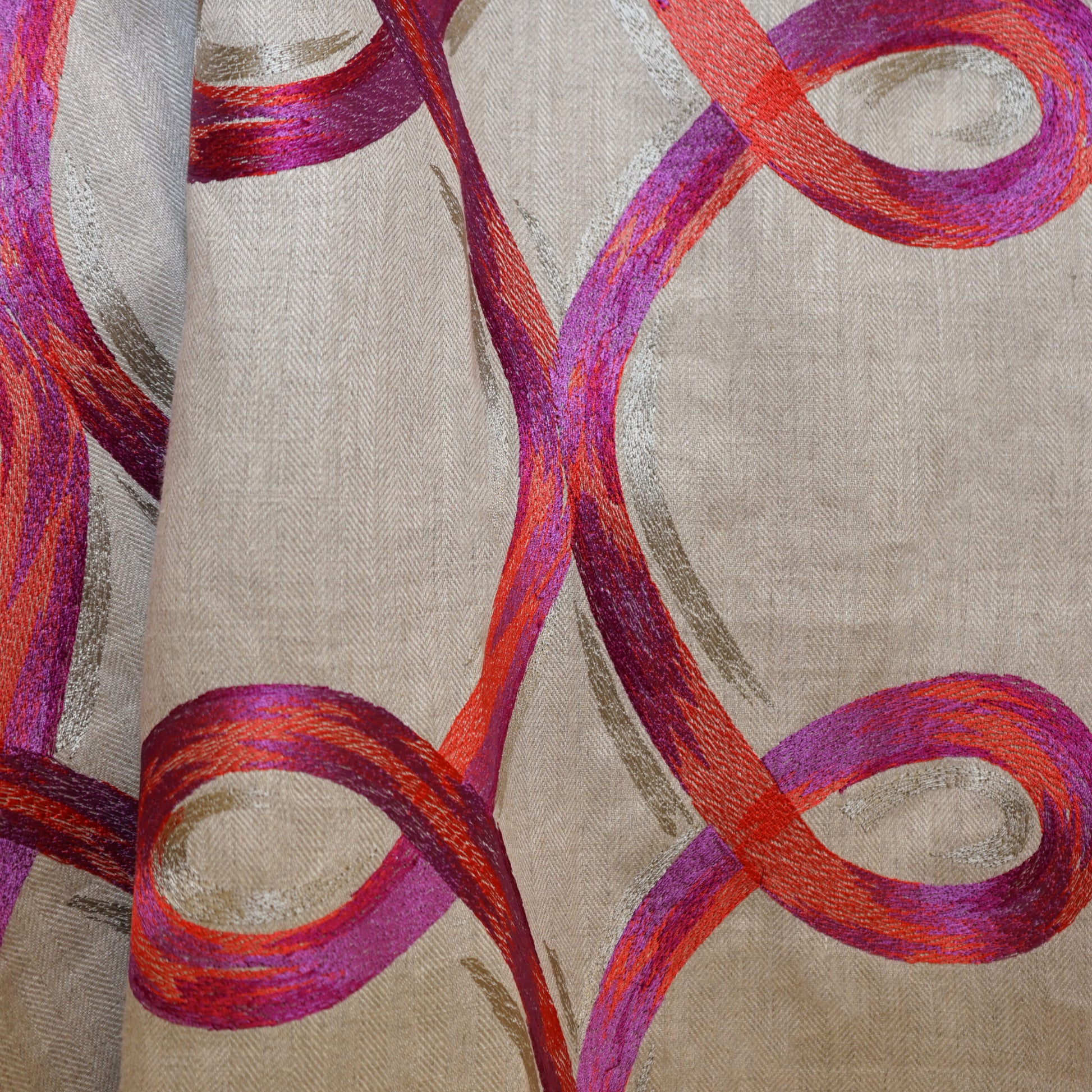 Beige drapery fabric with bold magenta and orange curved looping ribbon patterns.