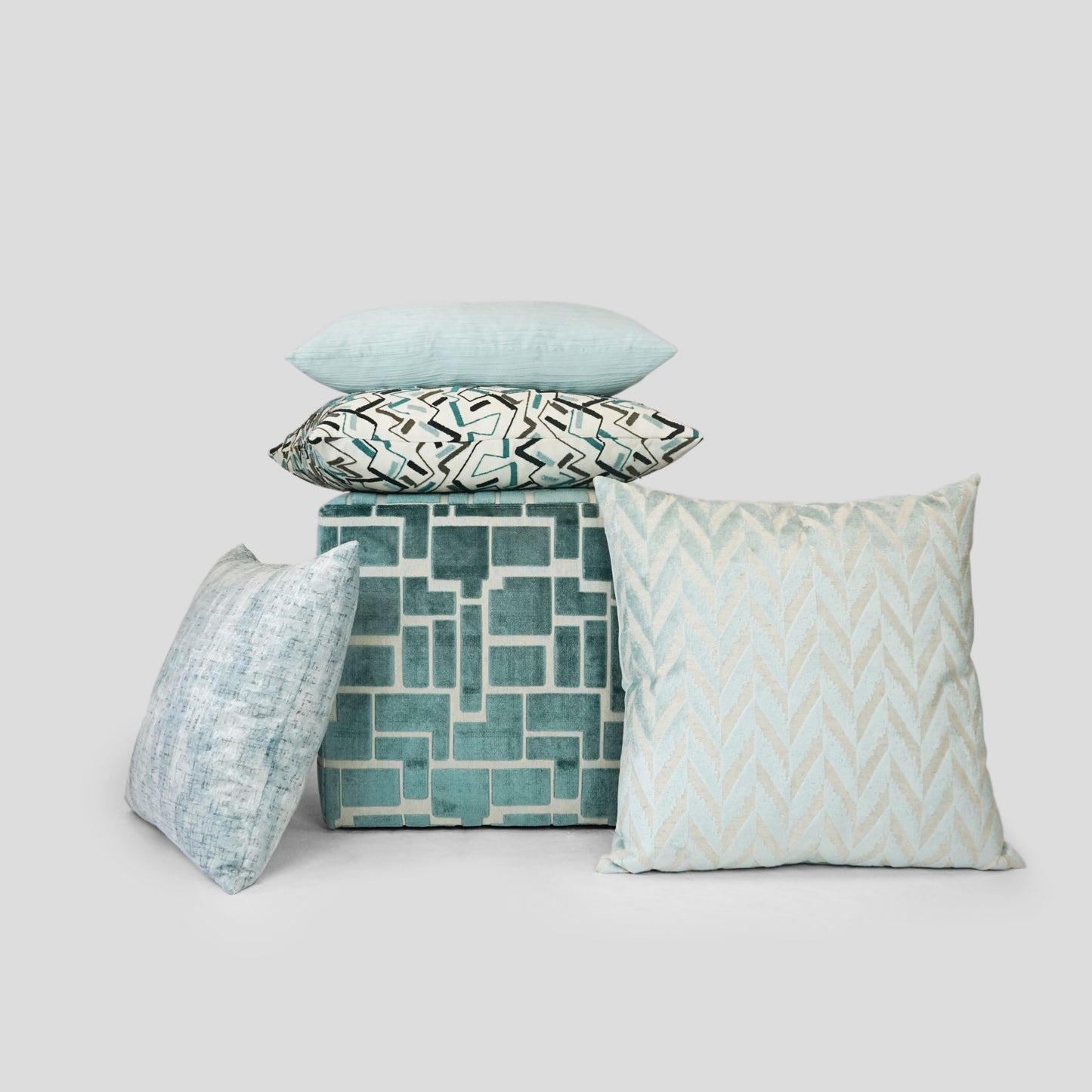 Set of solid teal ripple-textured throw pillows around a teal cube.