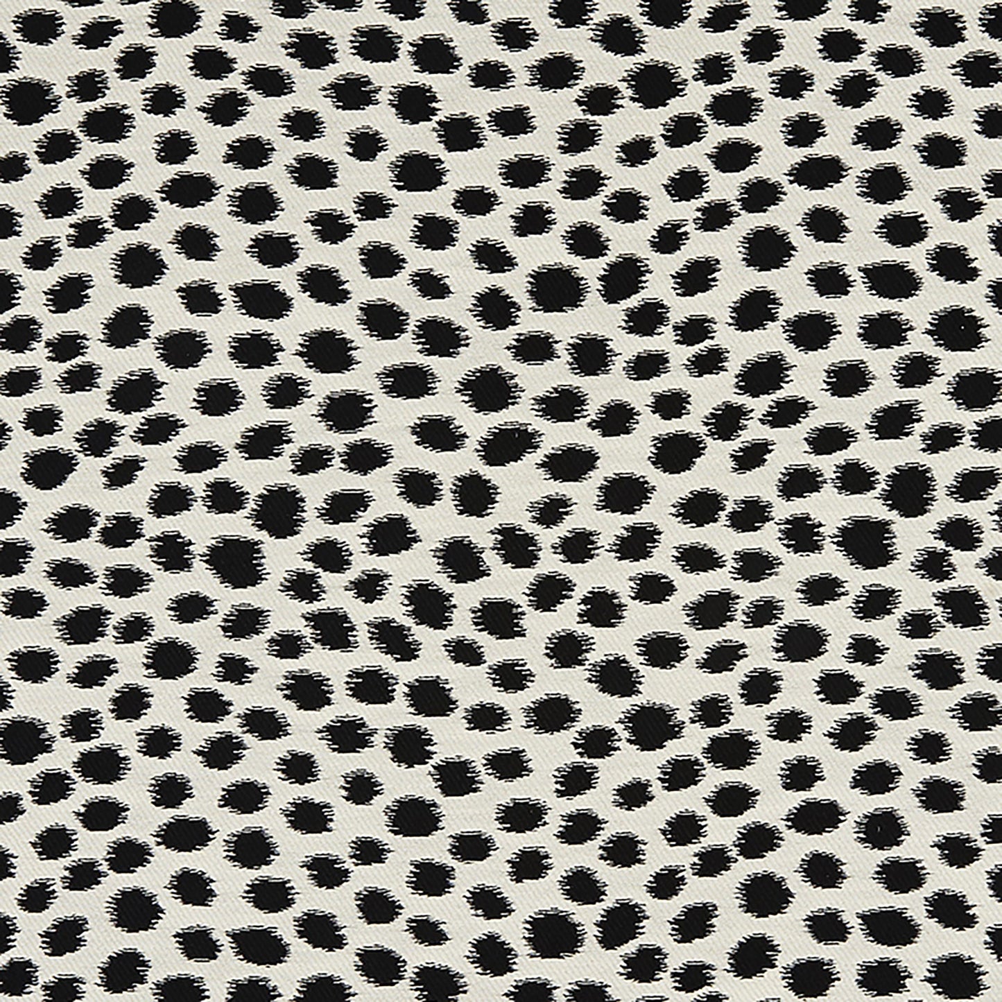 Dalmatian print fabric with irregular black spots on beige background.