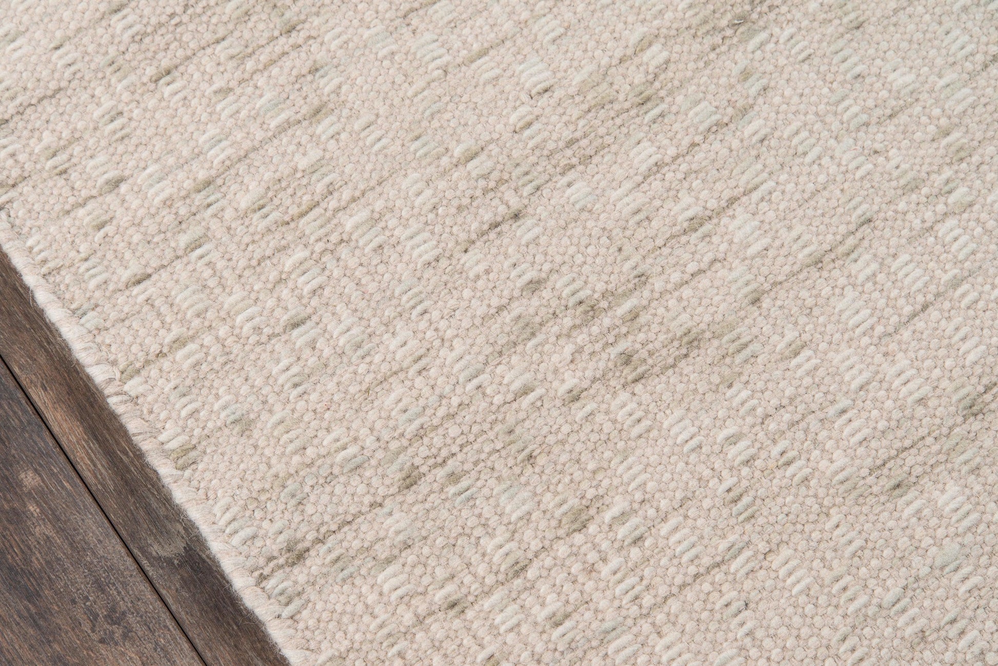 Beige textured area rug with a looped weave on dark wood flooring; casual cozy home decor.