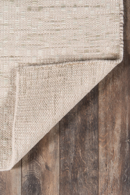 Beige woven rug corner folded over dark wooden floor; natural fiber texture, rustic & chic rug.