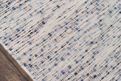 Rectangular woven area rug with a blue and ivory abstract pattern on a wood floor.