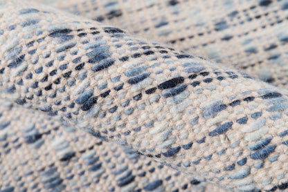 Blue and cream dotted pattern on a soft, woven rug; close-up texture.