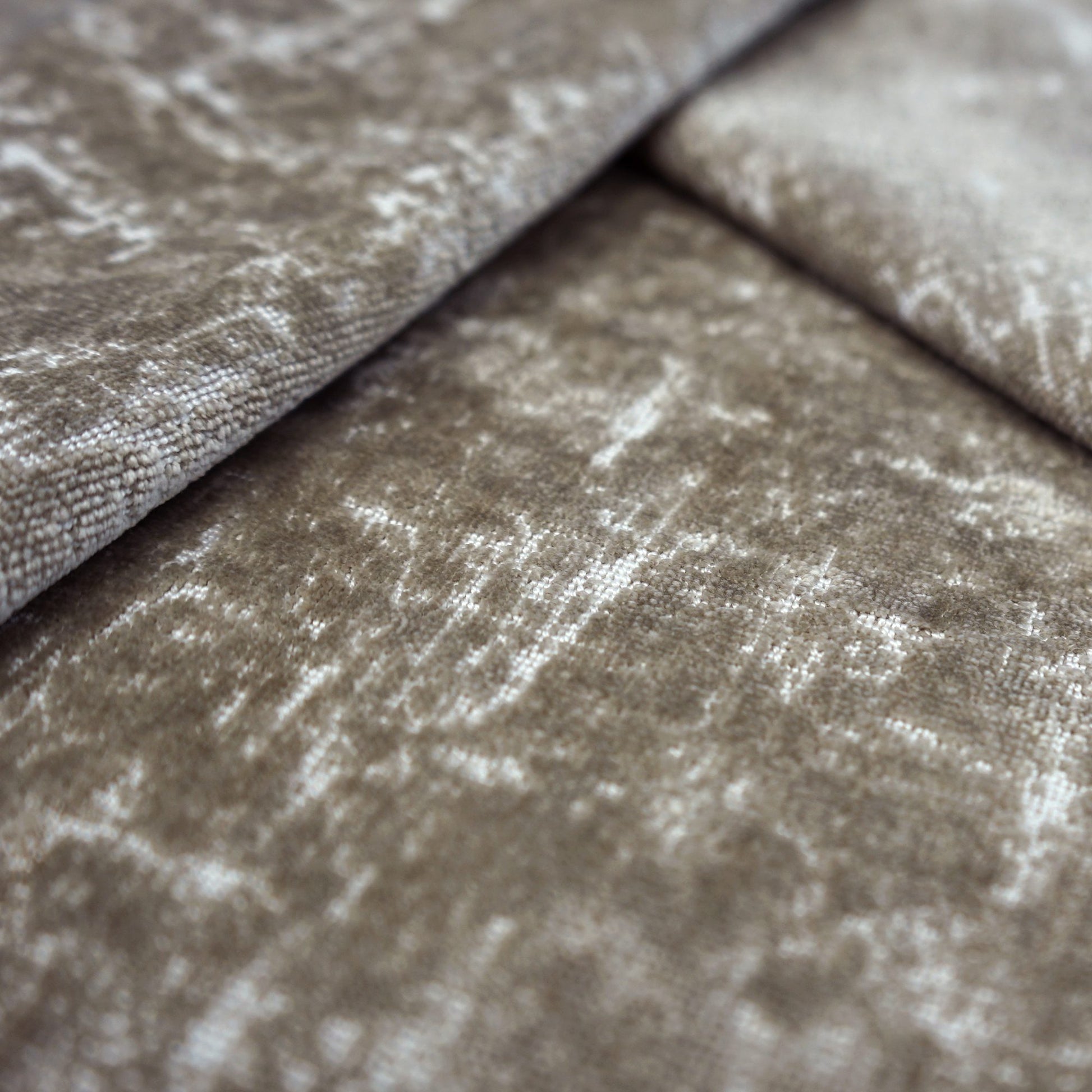 Close-up of taupe crushed-velvet fabric with subtle white highlights and plush, soft texture.
