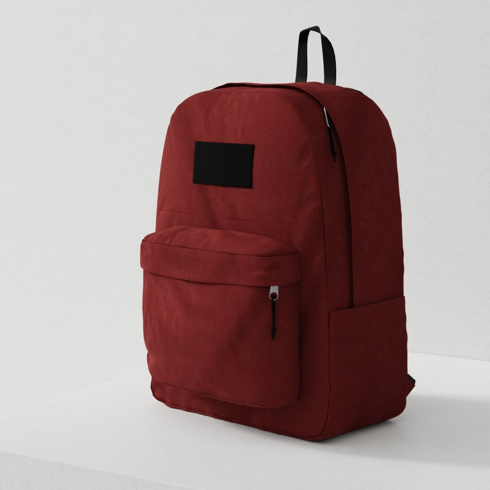 Red canvas backpack with black zippers, front zip pocket and black label patch; minimalist everyday carry bag.