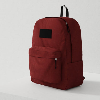 Red canvas backpack with black zippers, front zip pocket and black label patch; minimalist everyday carry bag.