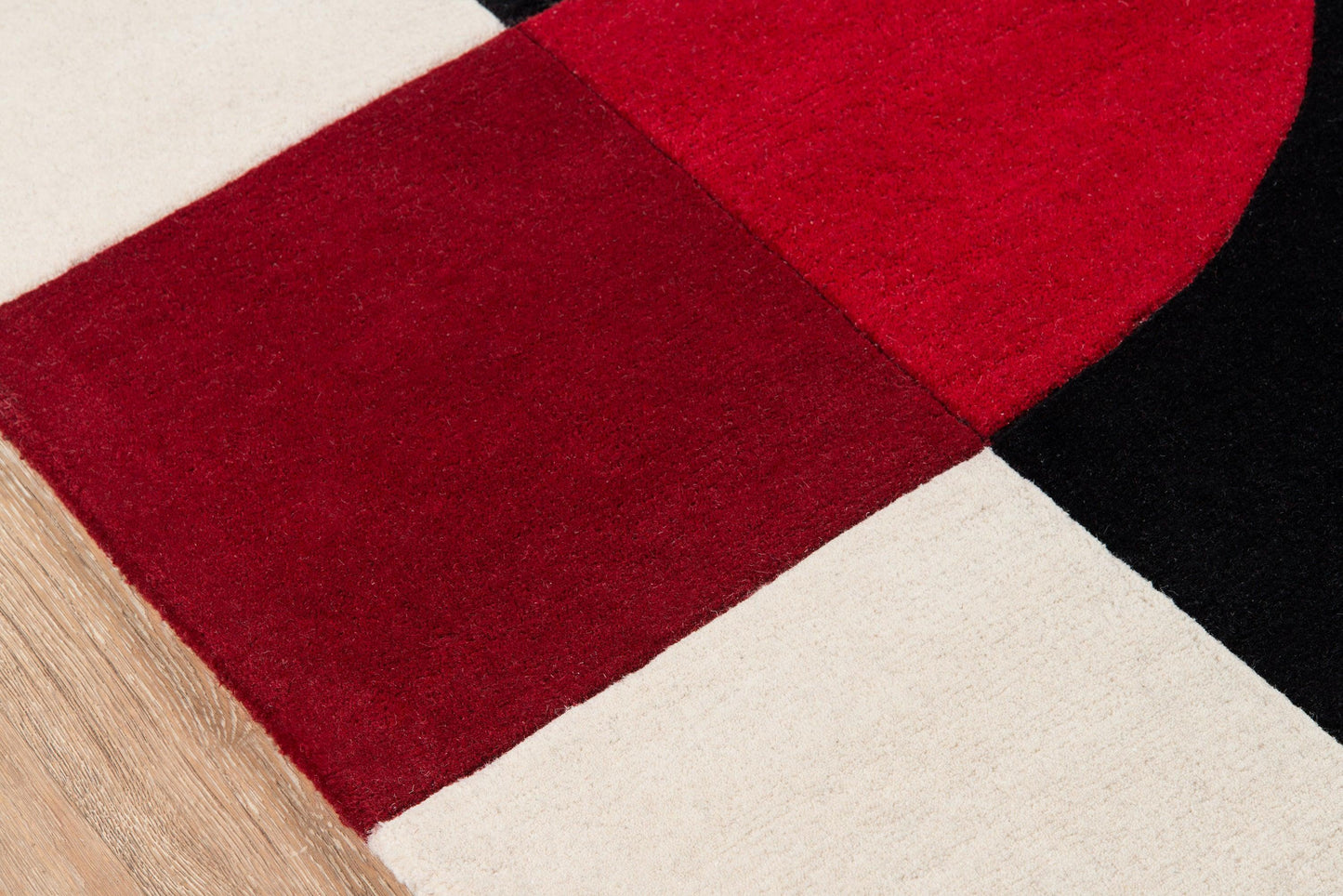 Geometric patchwork rug runner with cream, red, burgundy and black panels; textured close-up.