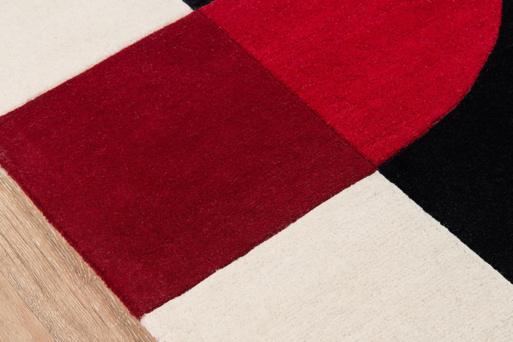 Color-block area rug in red, burgundy, black and cream with a soft pile.