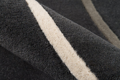 Close-up of a dark charcoal rug with a beige cream stripe, textured plush pile for modern living spaces.