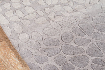 Gray pebble-pattern rug with irregular stone shapes; wooden floor edge visible