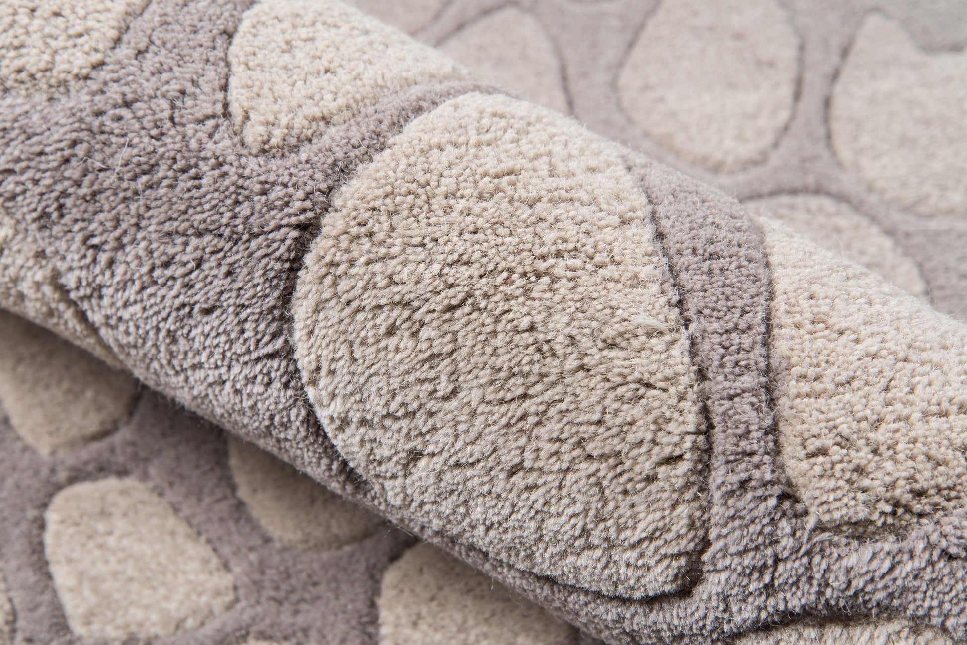 Close-up of a plush shag runner rug in taupe and beige tones, rolled edge, with circular tufted patterns for cozy home decor.
