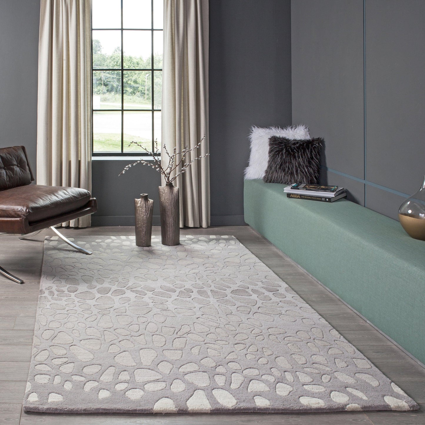 Light gray pebble-pattern area rug in a modern living room with charcoal walls and a green built-in bench.