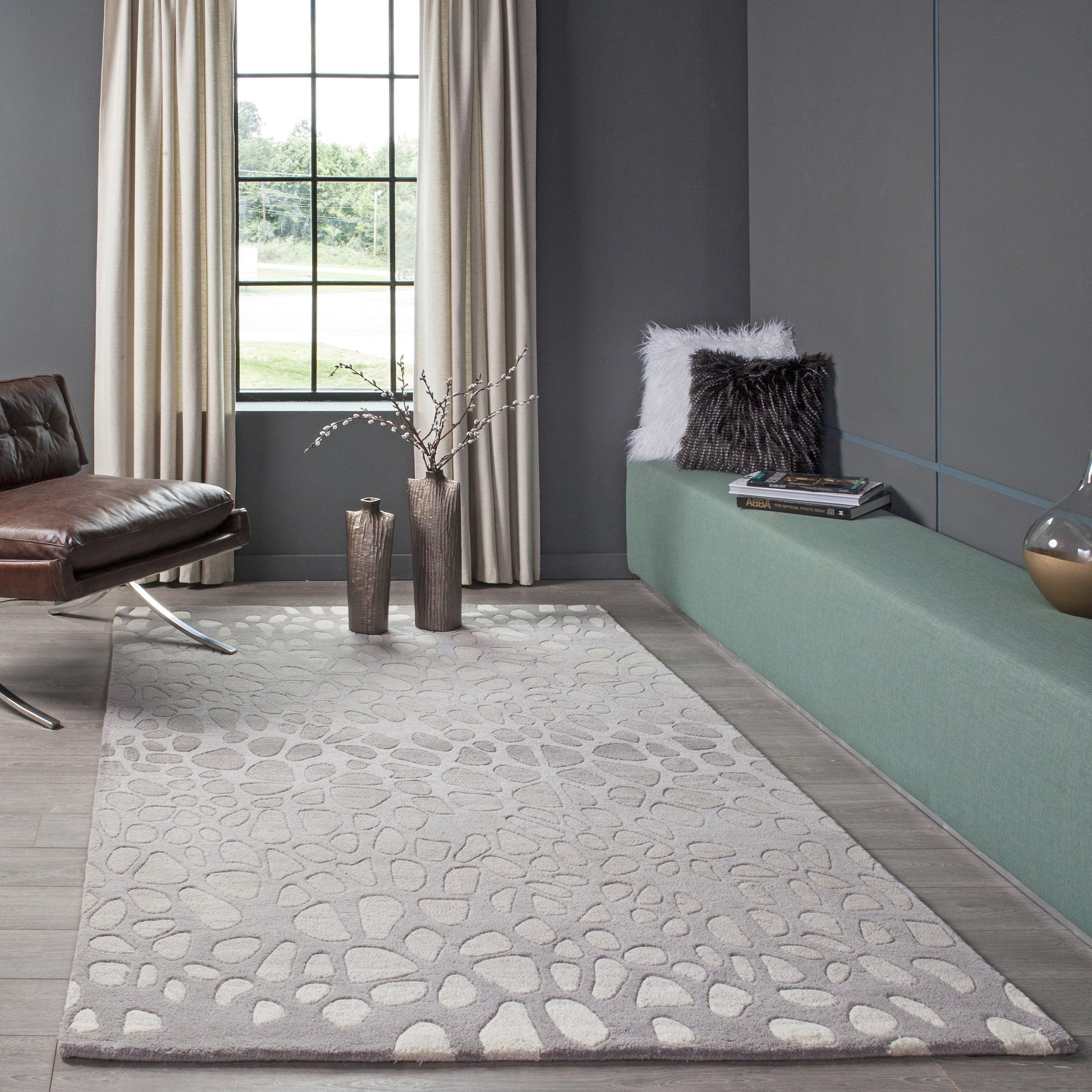 Light gray pebble-pattern area rug in a modern living room with charcoal walls and a green built-in bench.