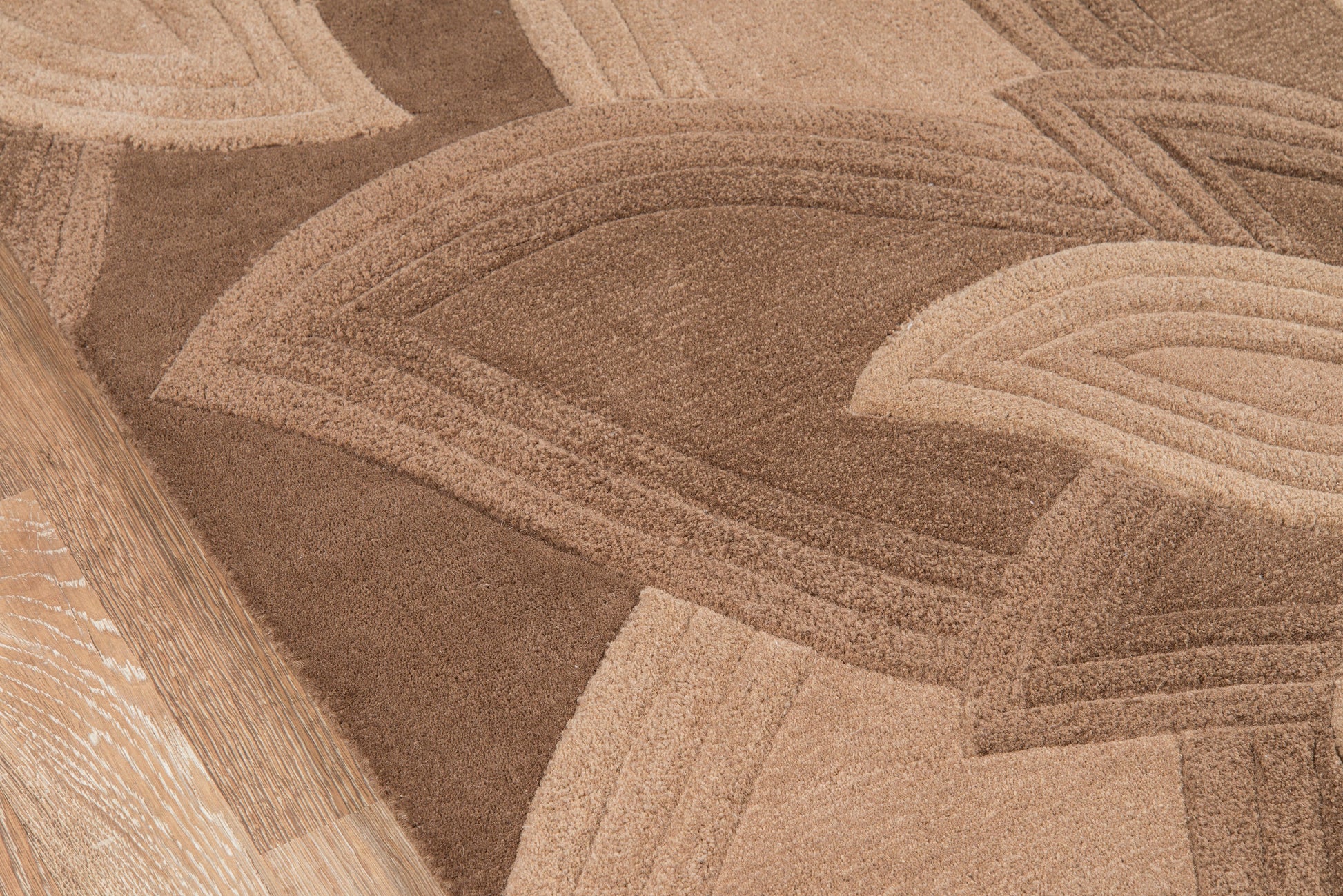 Beige and tan abstract rug with overlapping curved stripe patterns and a textured woven surface.