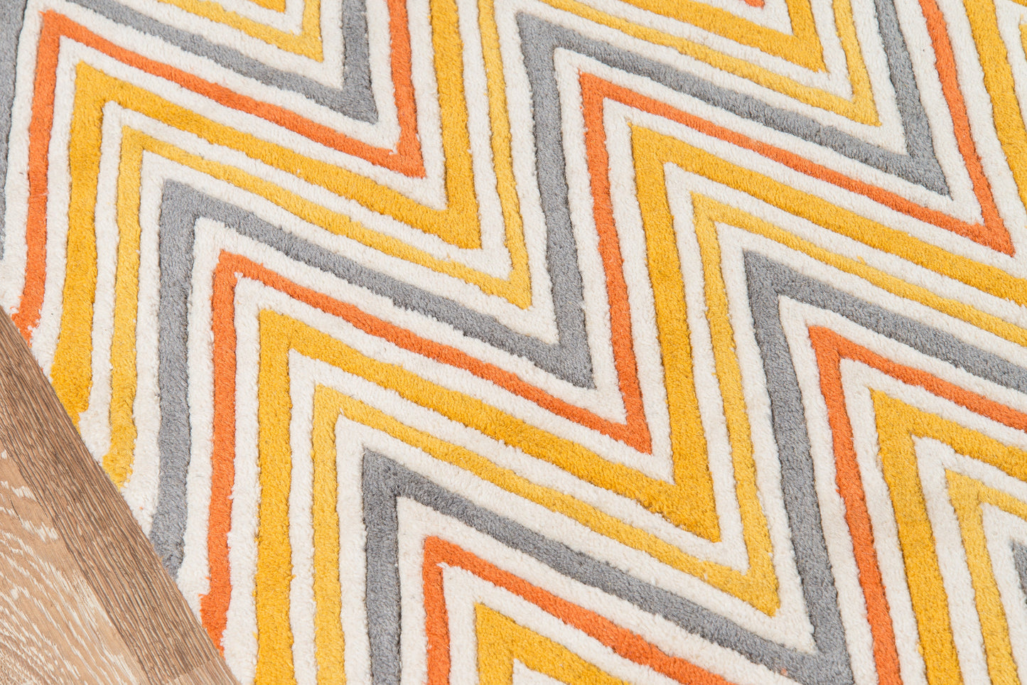 Chevron zigzag rug in orange, yellow and gray on white, retro mid-century style with wood floor edge.